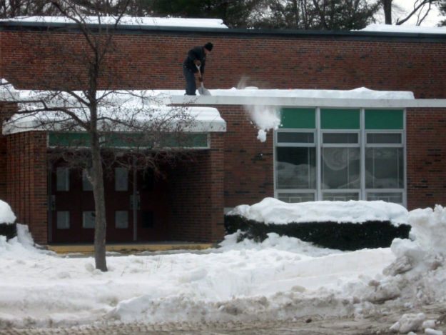 Man-shoveling-snow-off-school-roof